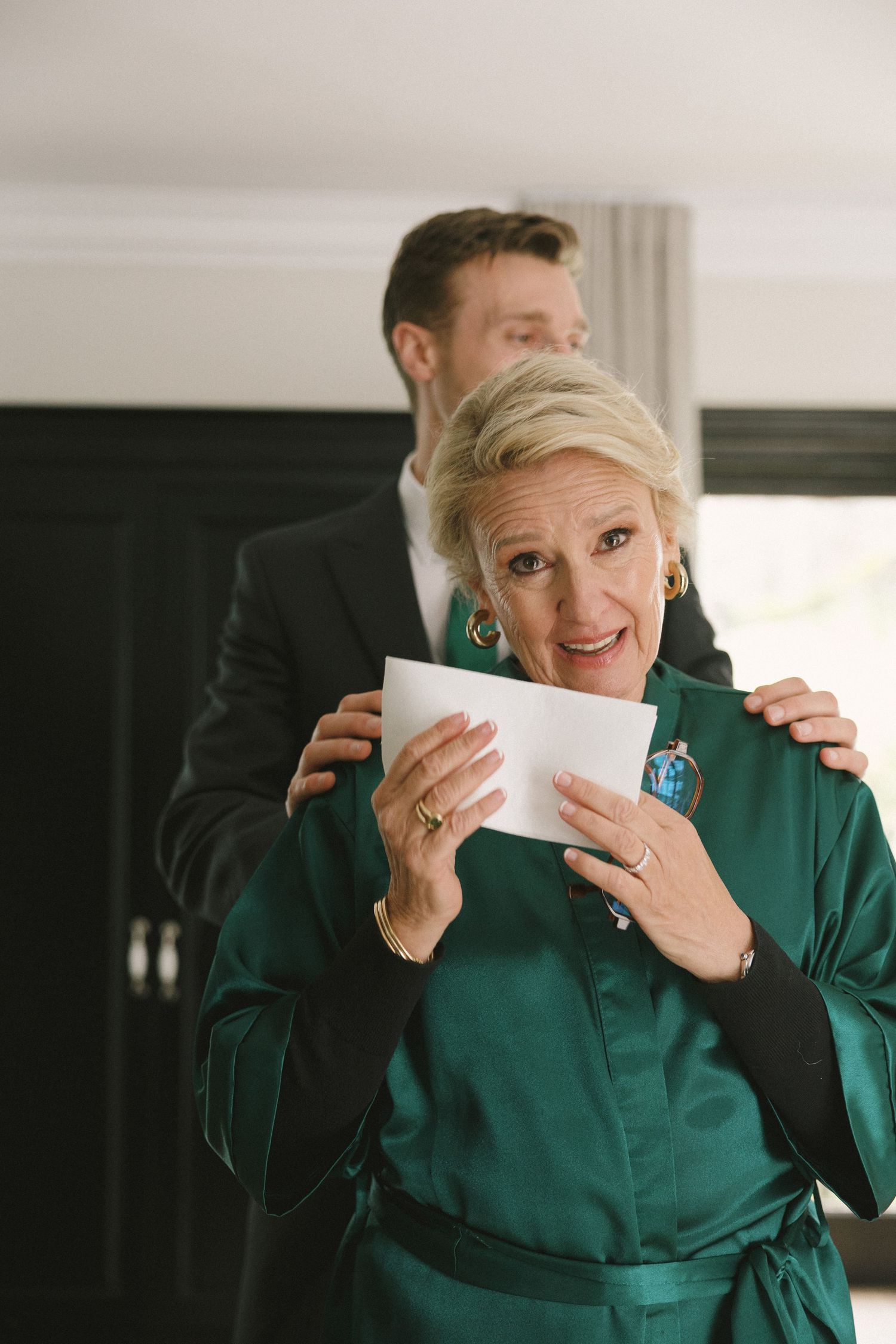A sequence of emotional reactions showing someone in an emerald green outfit holding papers.