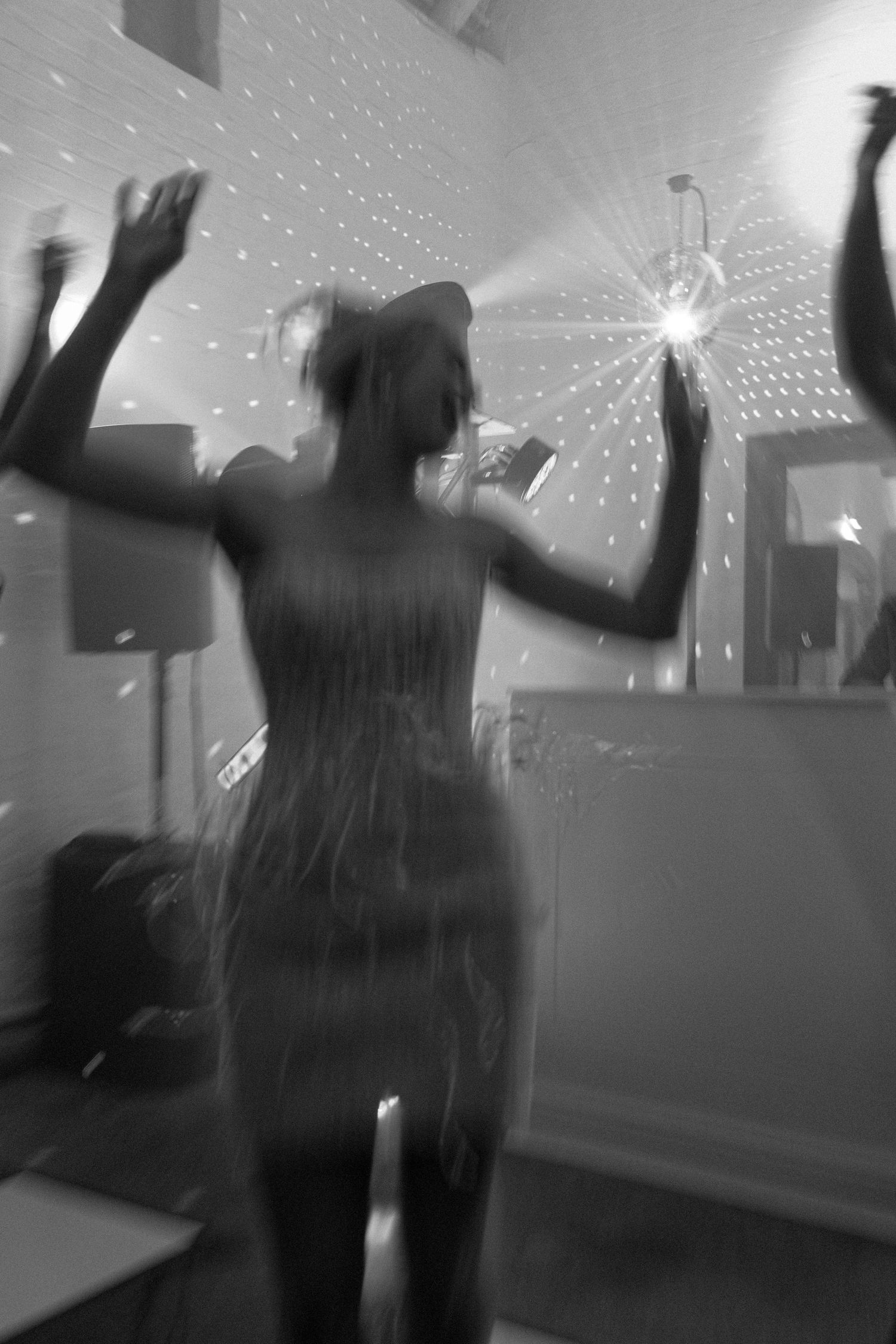 A series of blurry black and white photos showing a person dancing in a dimly lit room with sparkles or lights.