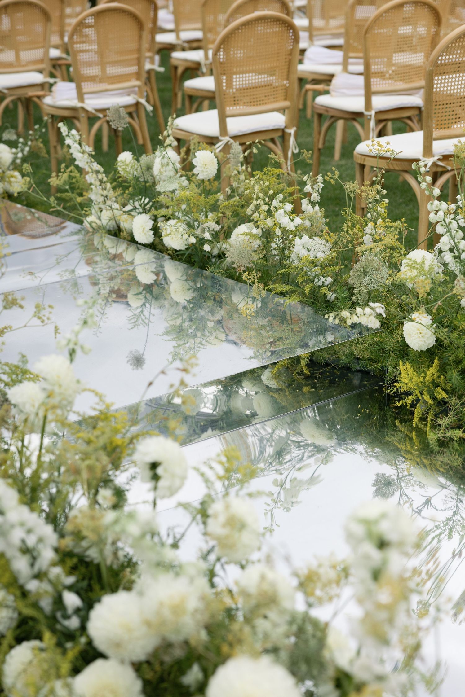Elegant white floral table arrangements with cascading greenery decorate a wedding reception venue.