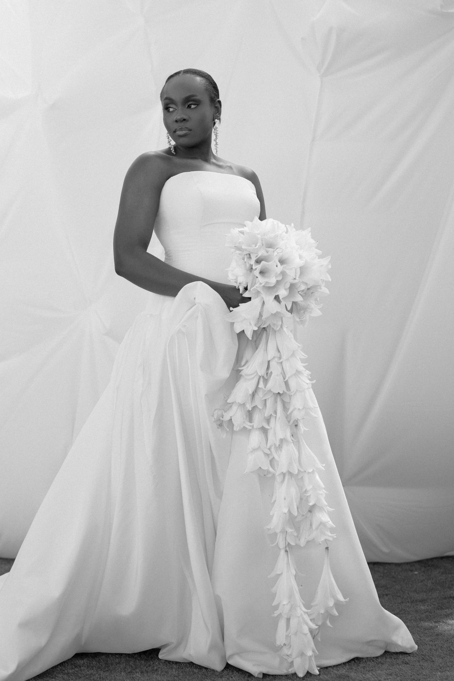 A series of four black and white wedding dress photos showing elegant white gowns with cascading floral details.