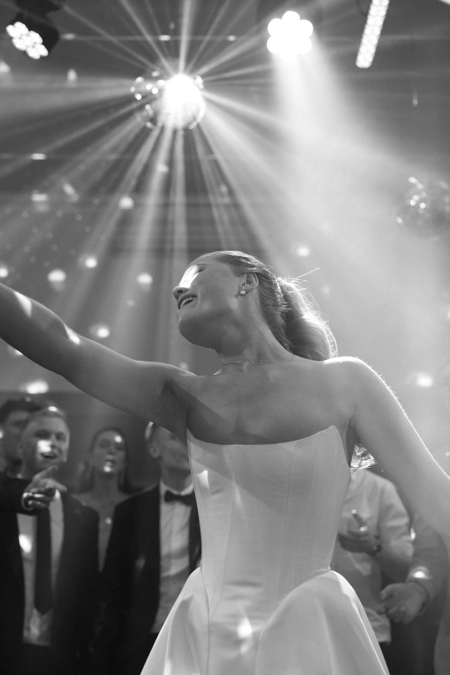 Dramatic dance sequence under spotlights at a wedding reception with flowing white dress movements.