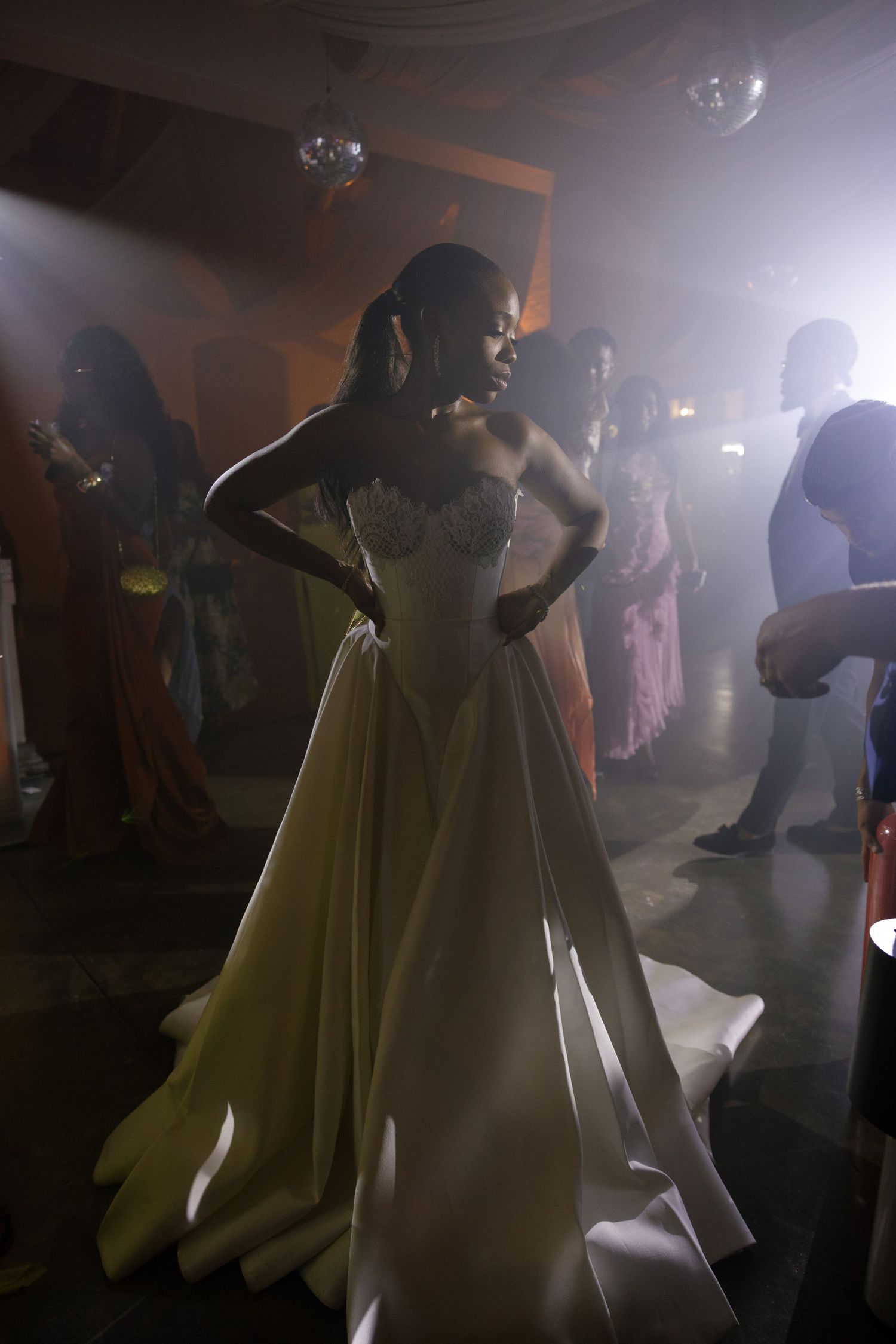 A couple dances together in a misty ballroom with dramatic lighting and flowing yellow dress.