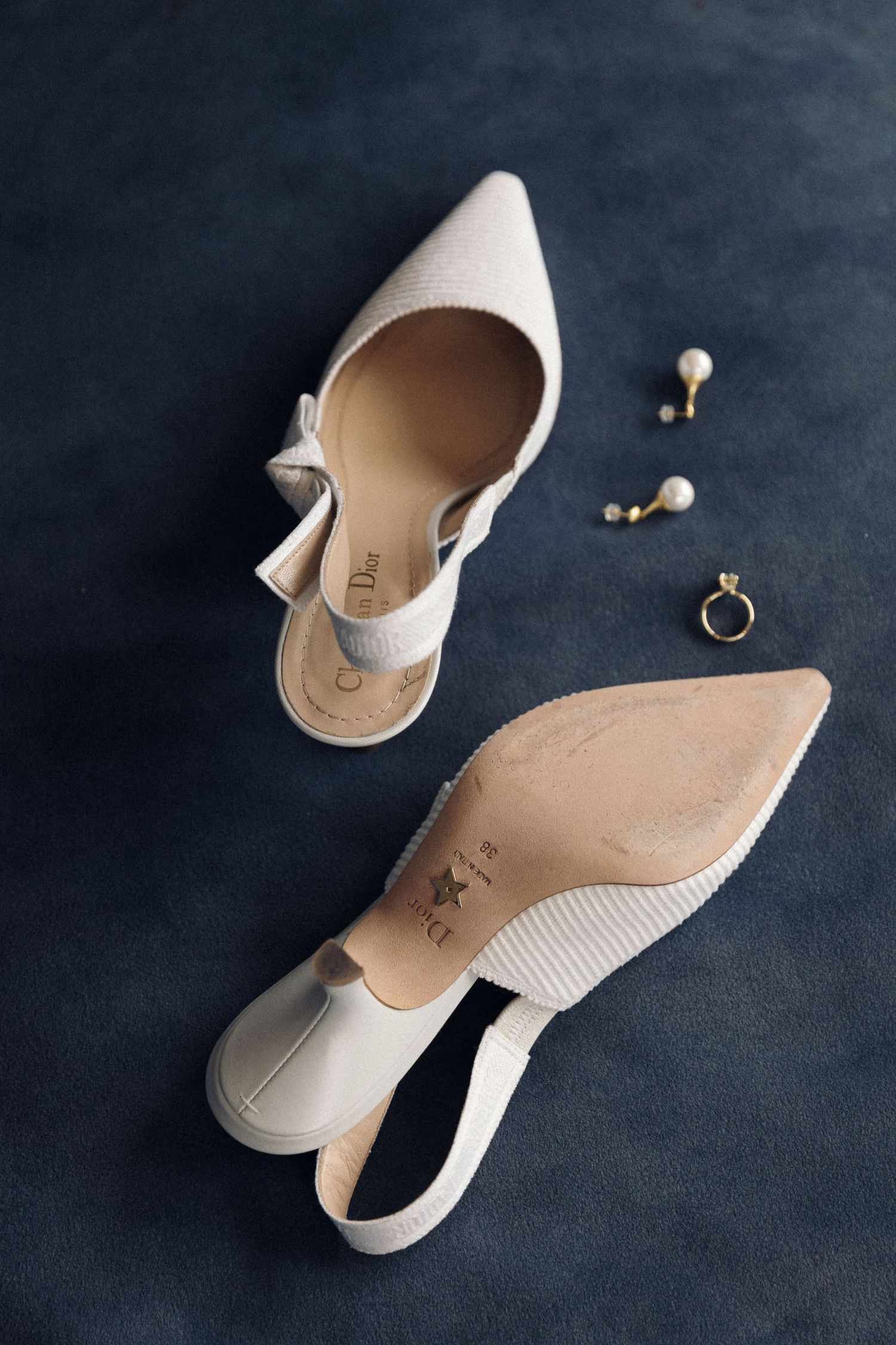 Elegant white leather ballet flats with pearl and ring accessories displayed on dark background in multiple angles.