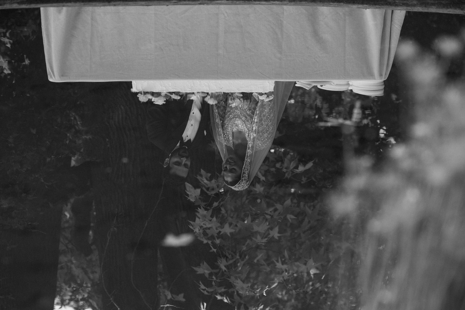 Black and white photo of a bat hanging upside down under a white cloth in a dark outdoor setting.