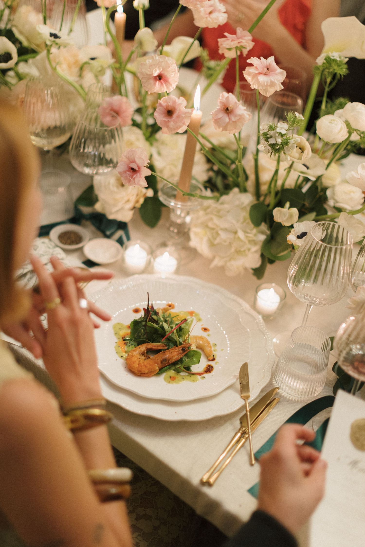 Elegant table setting with pink flowers and plated meals at an upscale dining event.