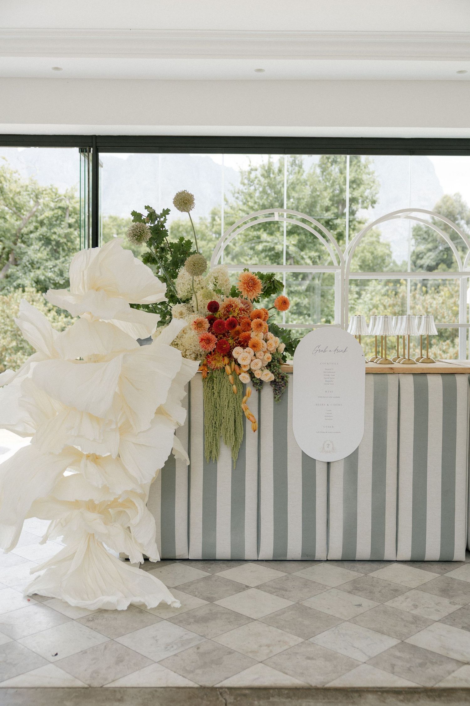 A beautiful floral arrangement with large white flowers and colorful accents on a tiled floor in front of a window.