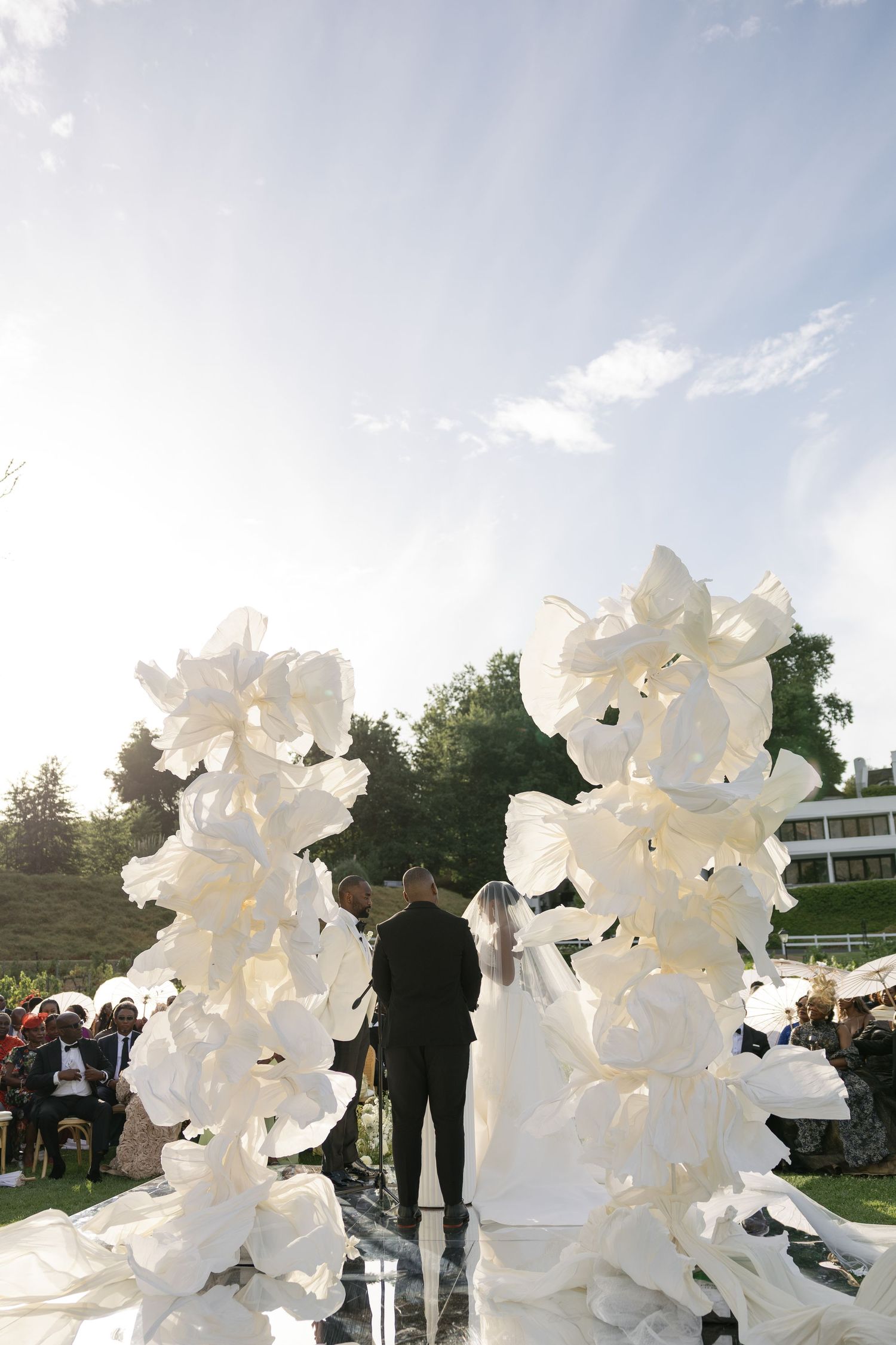 Large white abstract sculptures made of plastic bags and wire frames create an ethereal outdoor art installation.