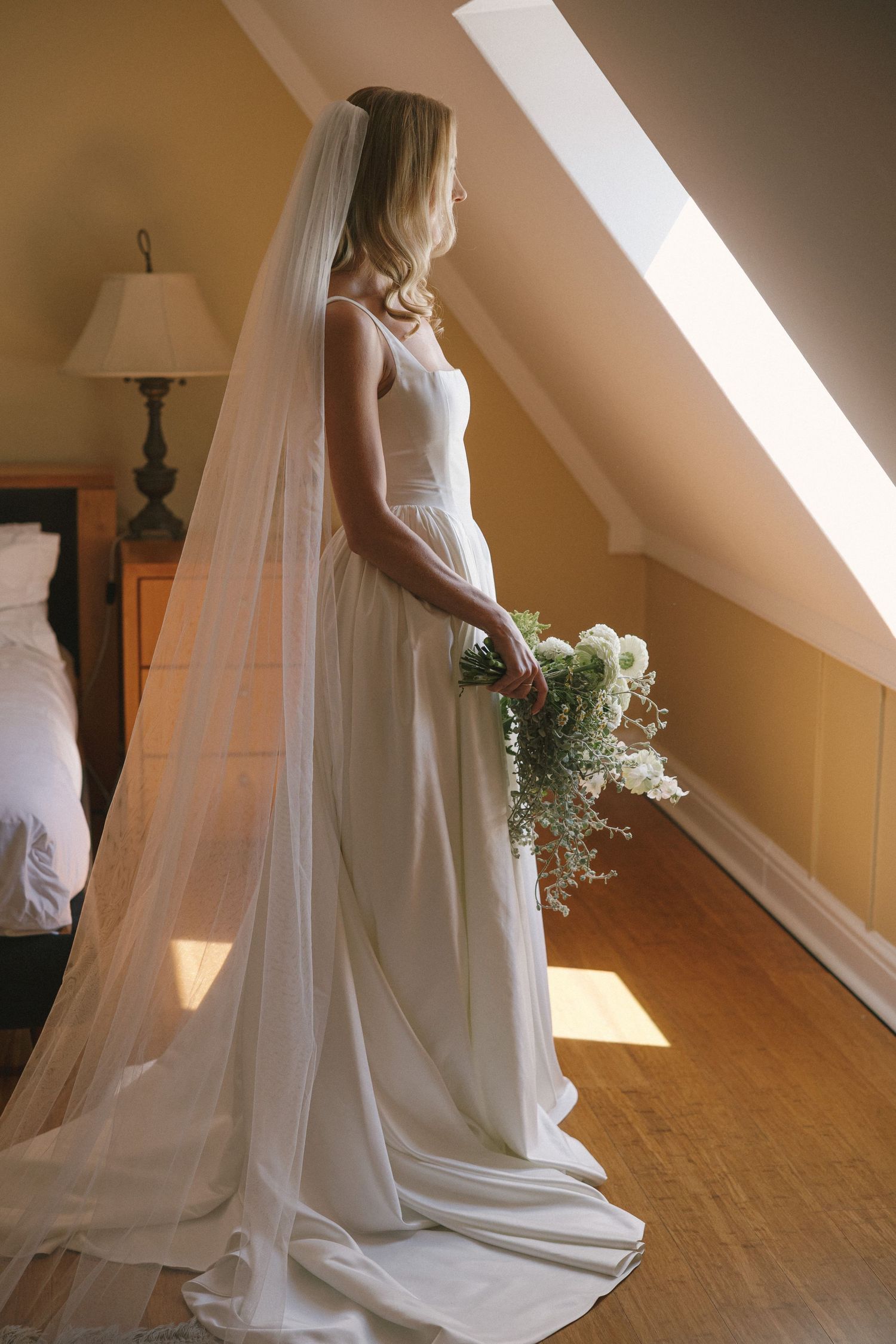 A series of wedding dress photos showing a flowing white gown with a long veil in natural window light.