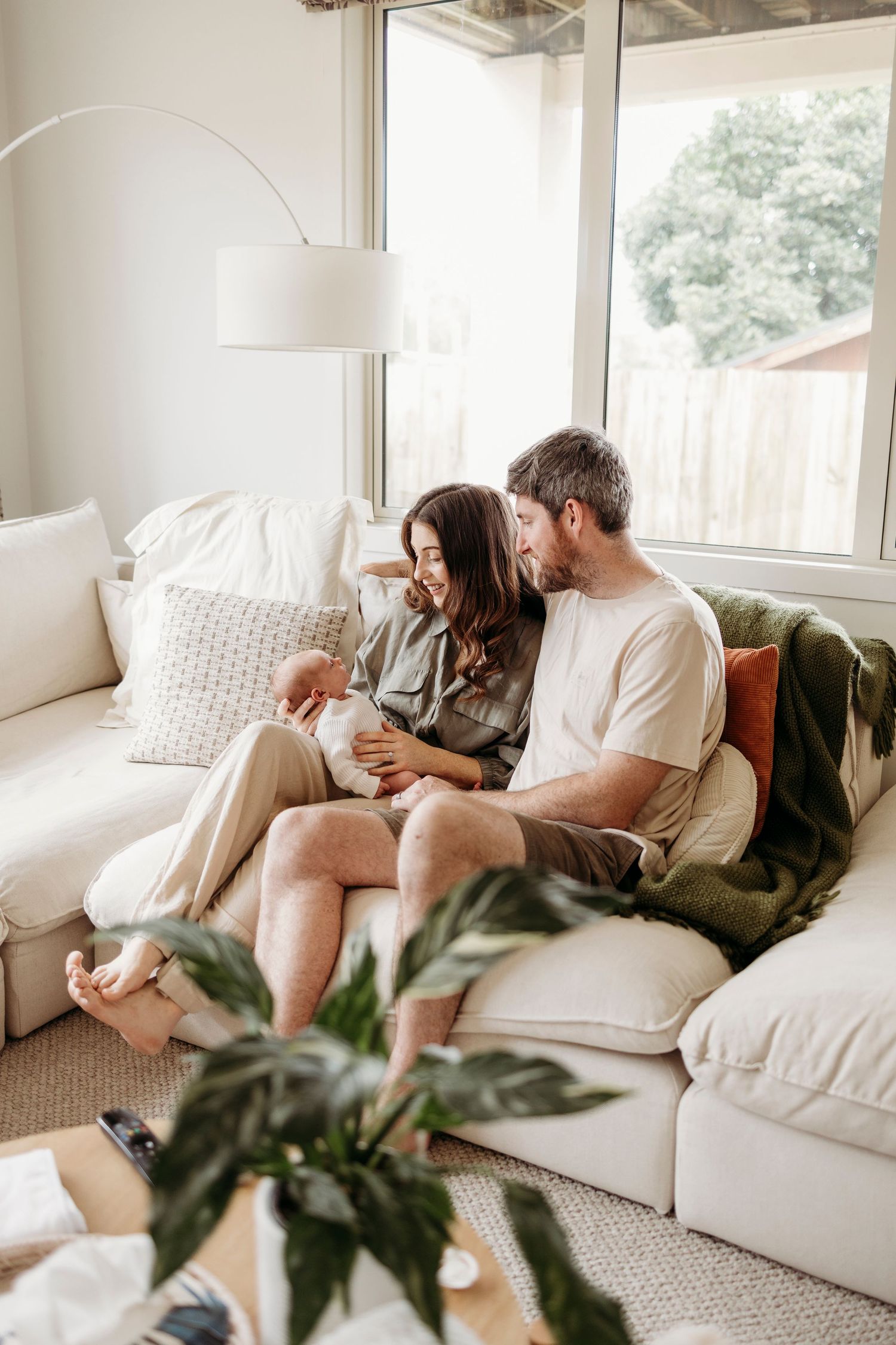 Happy couple sitting together on a white sofa in a bright living room, sharing a warm and intimate moment.