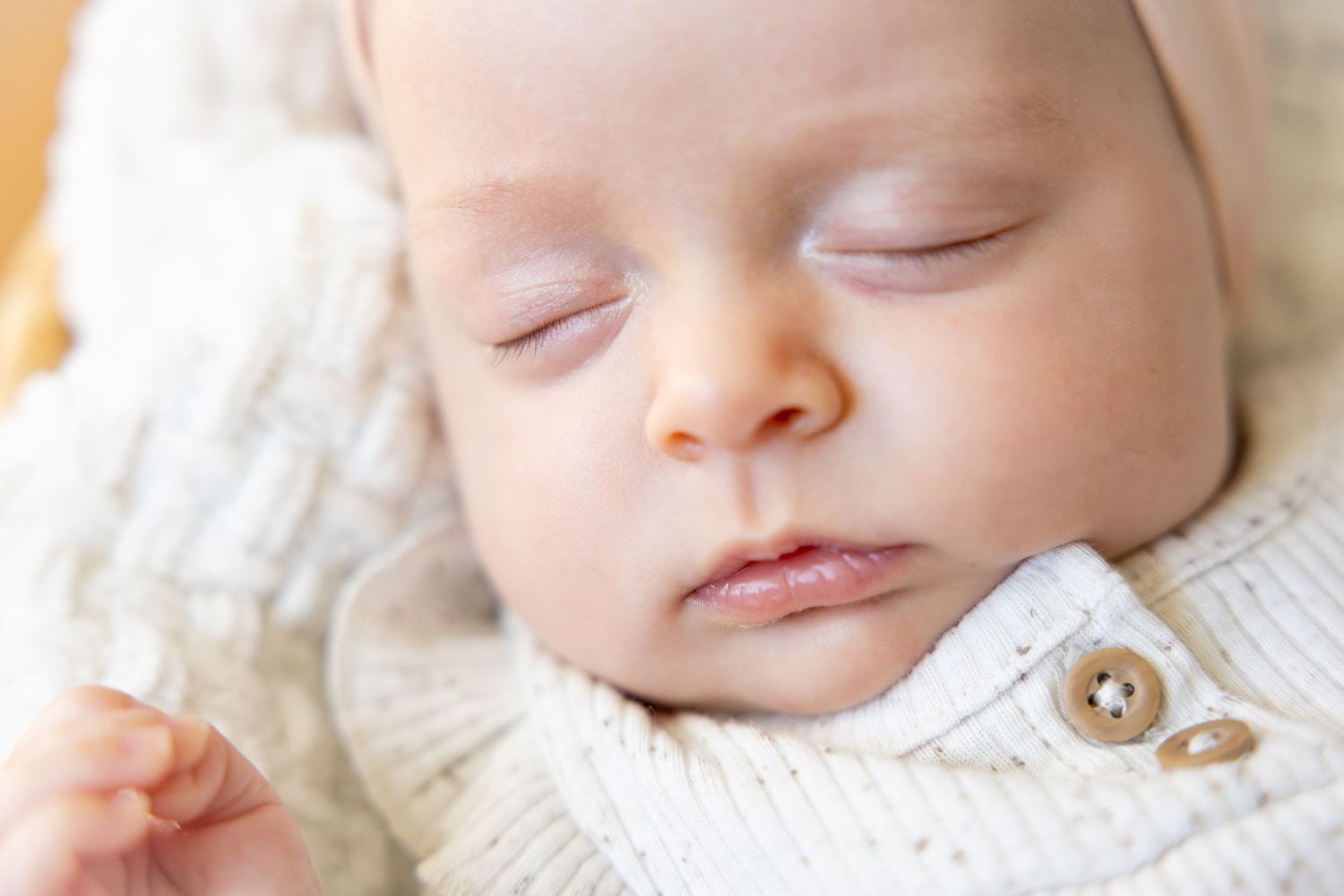Close up of peaceful sleeping baby in cream colored knit sweater.