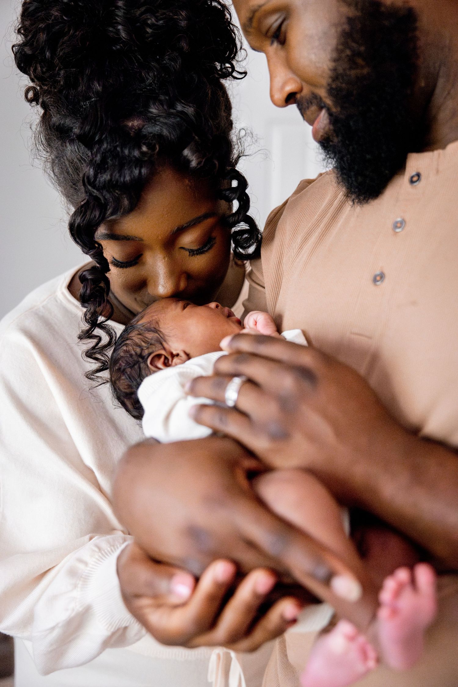 Close up of tender moments between parent and newborn swaddled in soft fabrics.