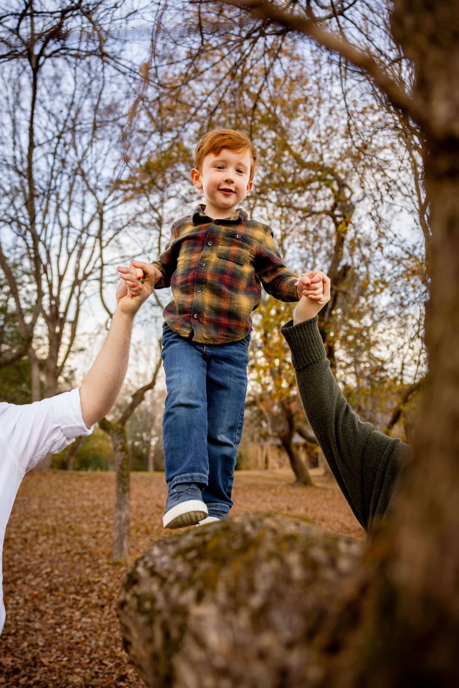 Child being lifted playfully among fallen autumn leaves.
