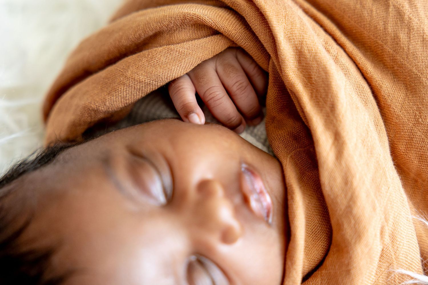 Peaceful sleeping portrait wrapped in soft caramel fabric shows gentle features.