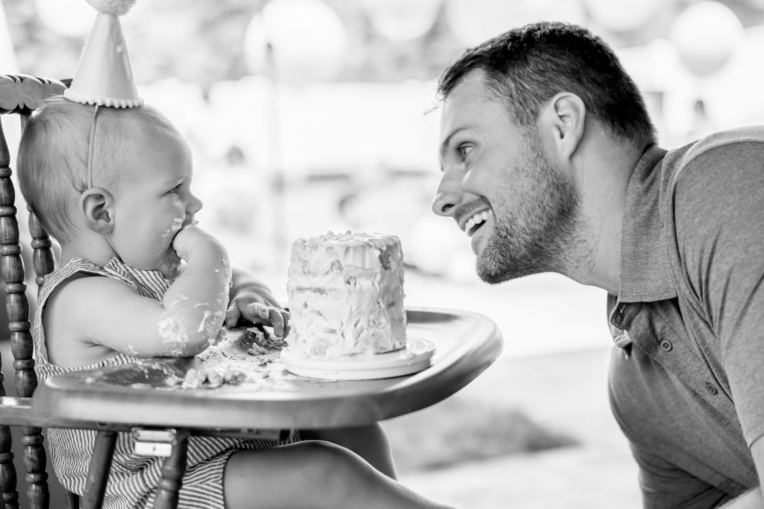 Black and white capture of joyful cake smash moment at first birthday celebration.