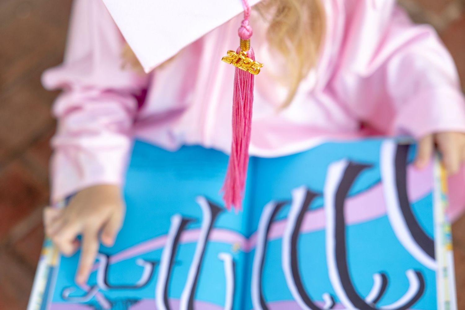 Close-up of pink graduation tassel against blue background.