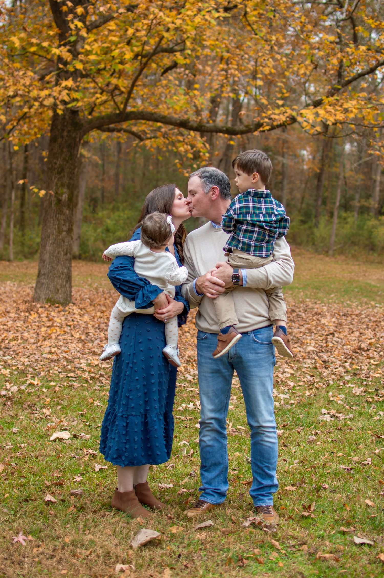 Family shares tender moment together surrounded by golden autumn leaves at Westminster Park in Rock Hill, SC.