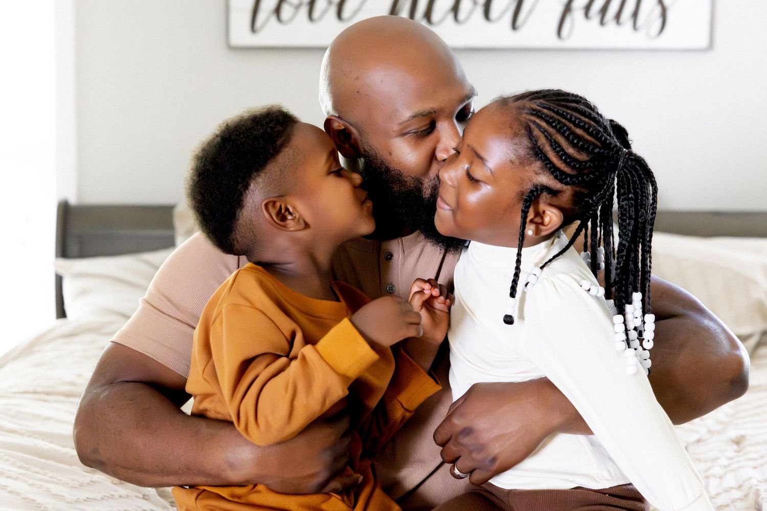 Heartwarming interactions captured on white bedding with 'love never fails' wall art visible.