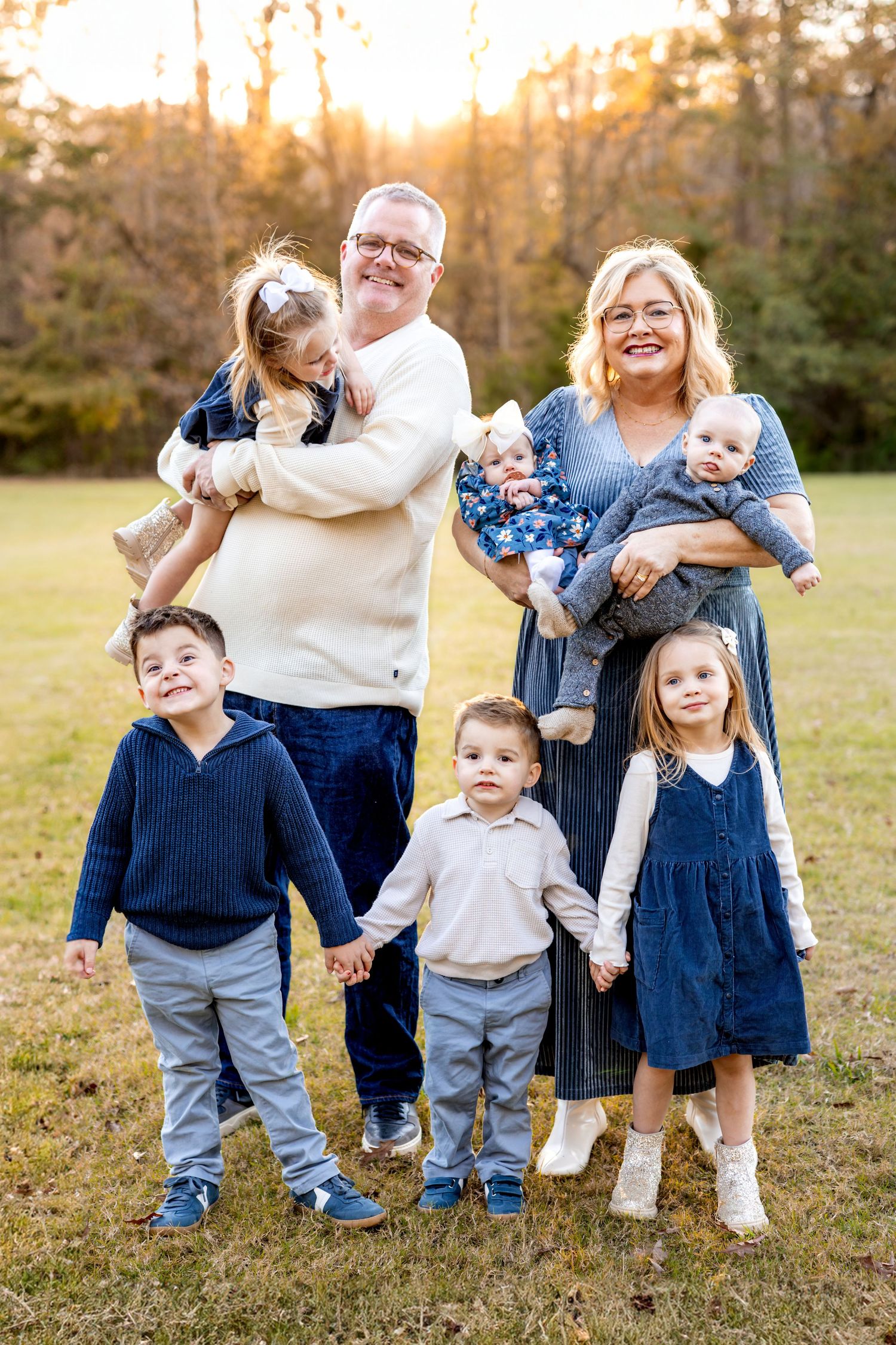 Casual family group portraits with coordinating blue and white outfits in a park setting.