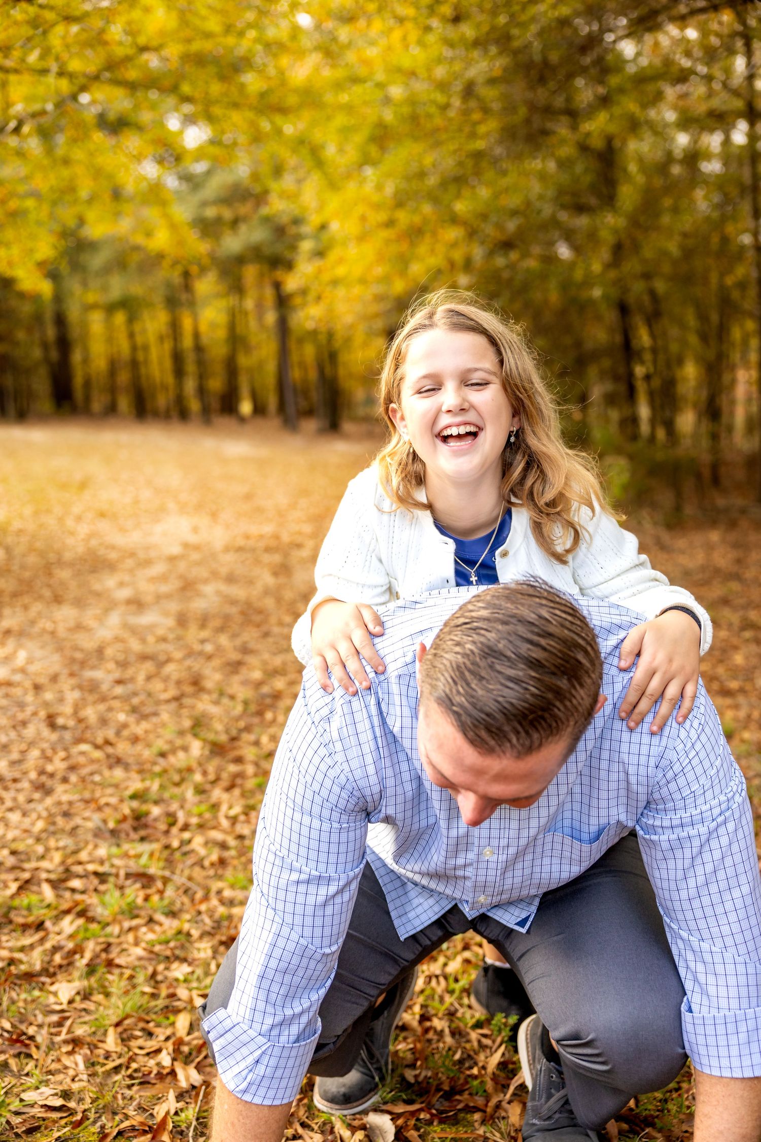 Playful autumn scene with two people having fun among fallen yellow leaves.