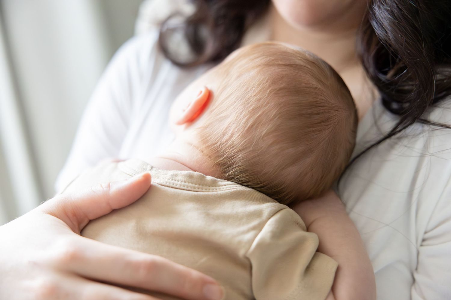 Close up of infant being held in white shirt.