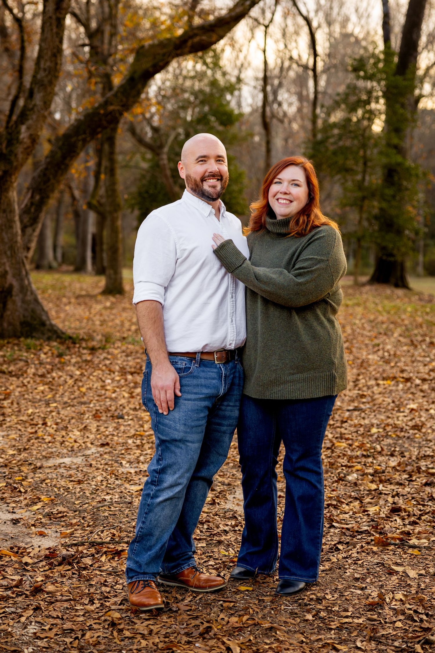 Casual outdoor family portrait session with everyone wearing blue jeans against autumnal woodland backdrop.