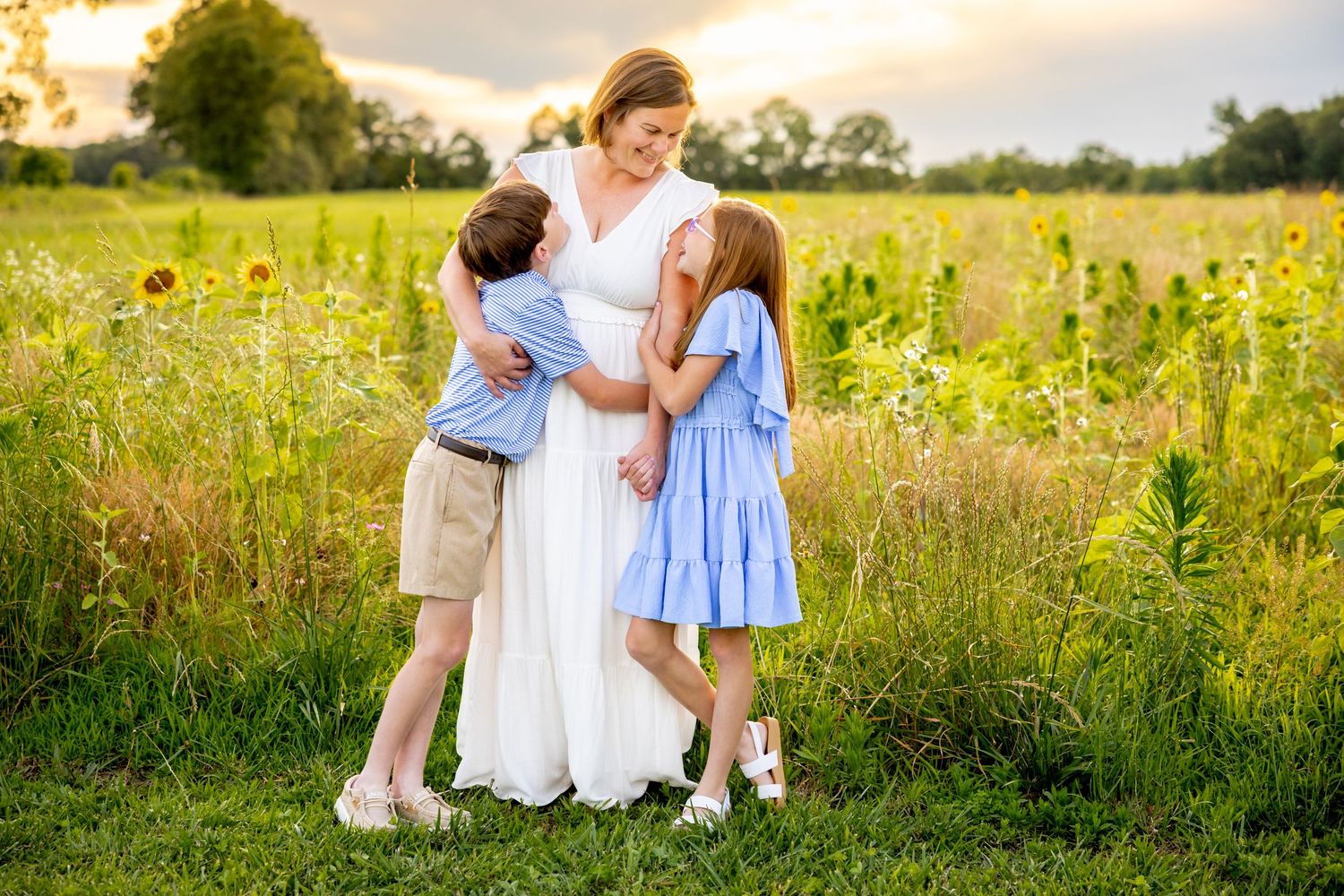 A loving family embrace in a summer field with golden light and wildflowers at Blue Hill Garden in Monroe, NC.