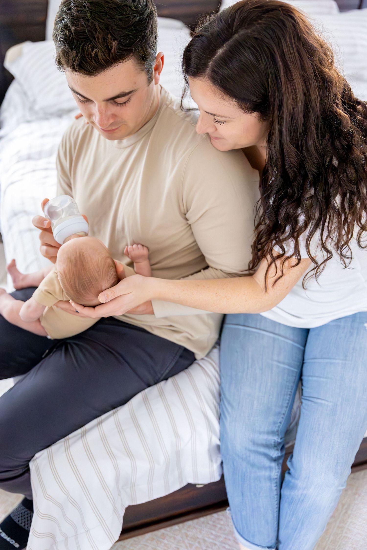 Intimate family moment with newborn on white bedding.