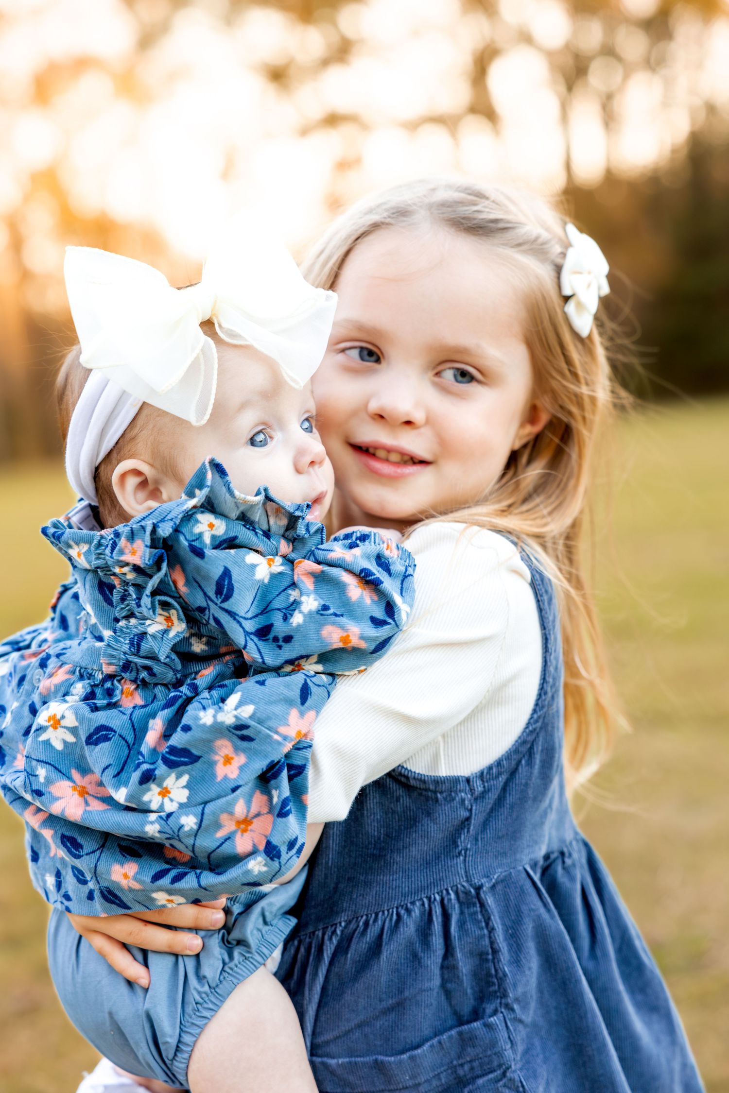 Close up of children holding and playing with blue floral patterned dolls.