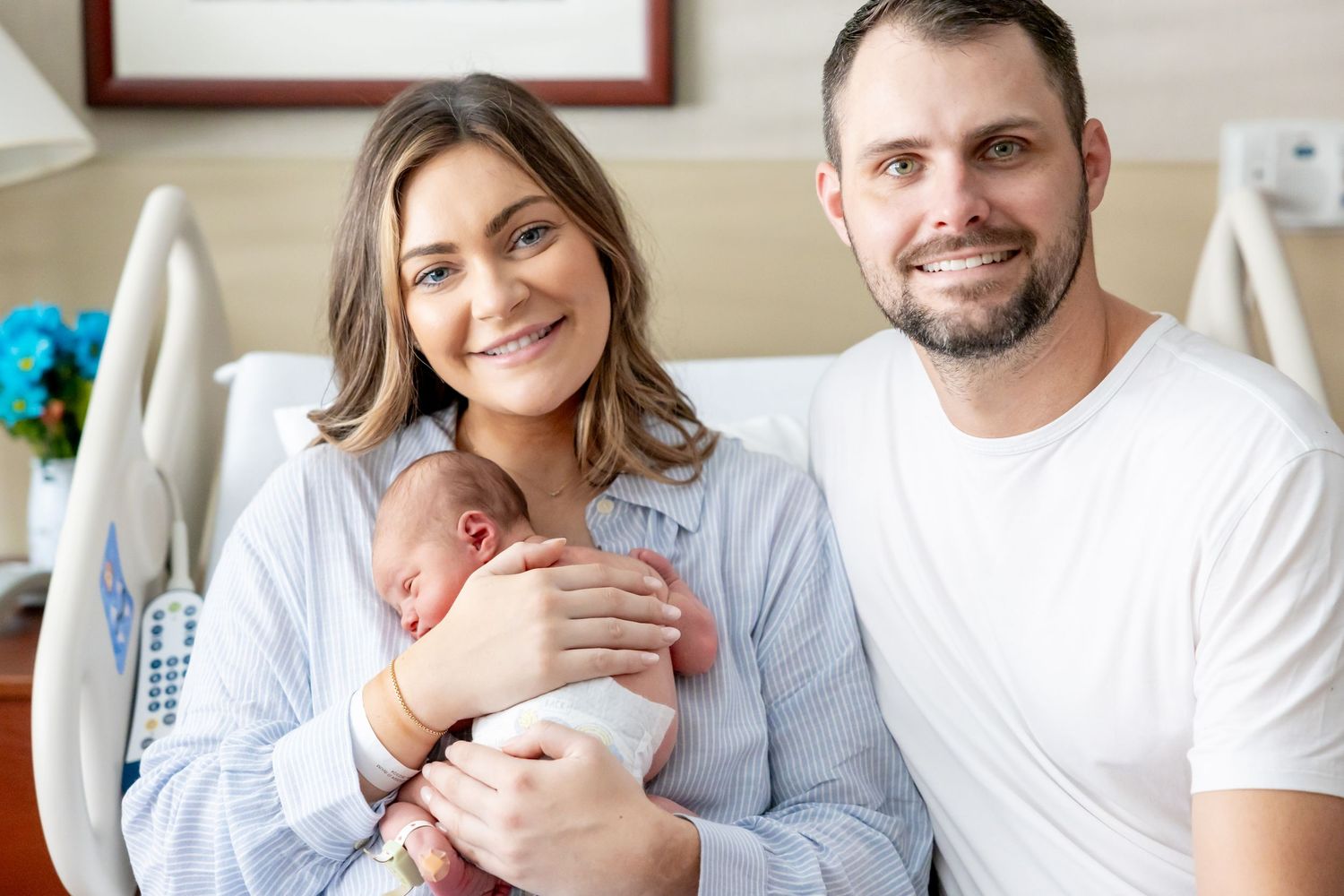 Happy new parents with their newborn baby in hospital room.
