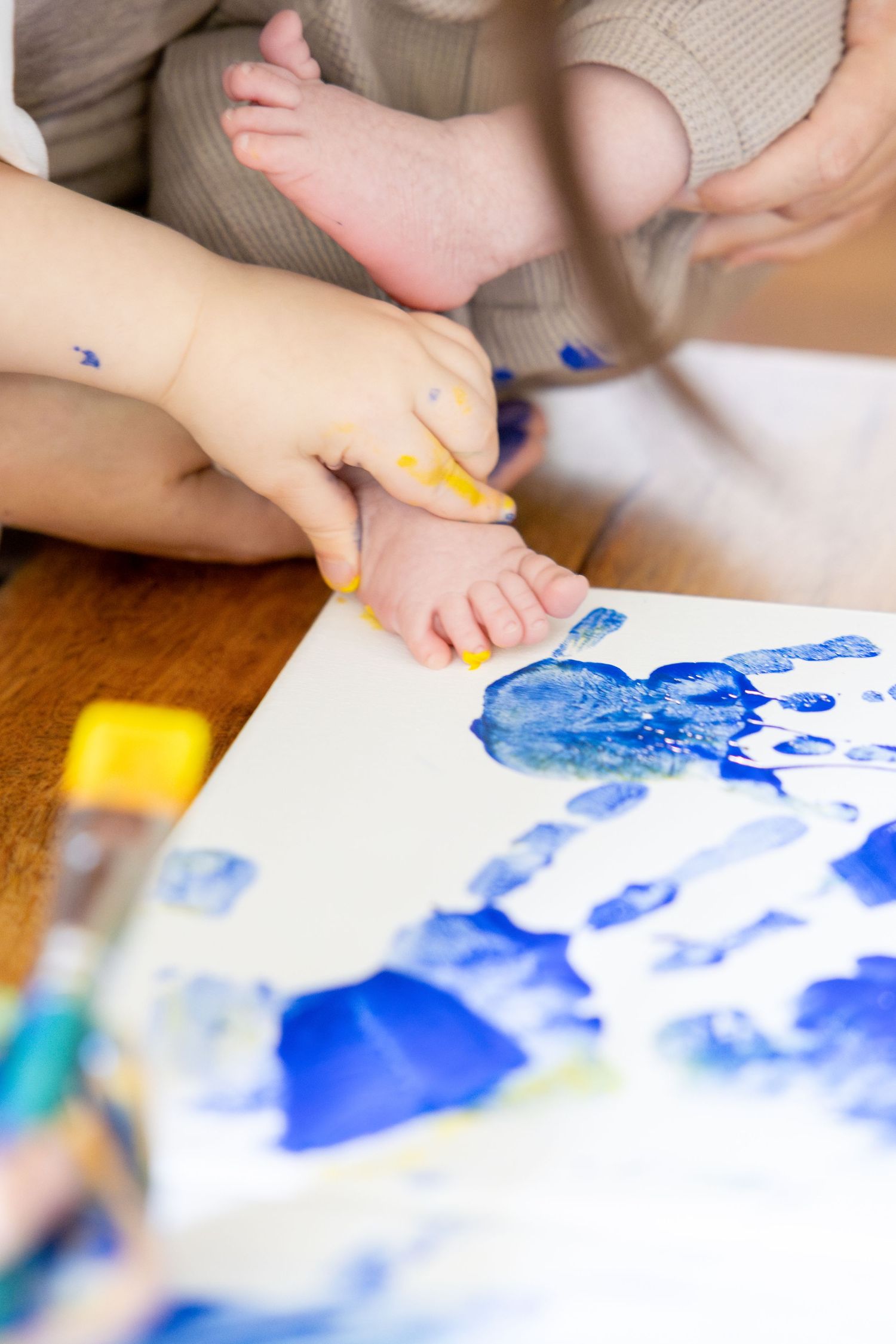 Close up of hands creating blue watercolor art on white paper.