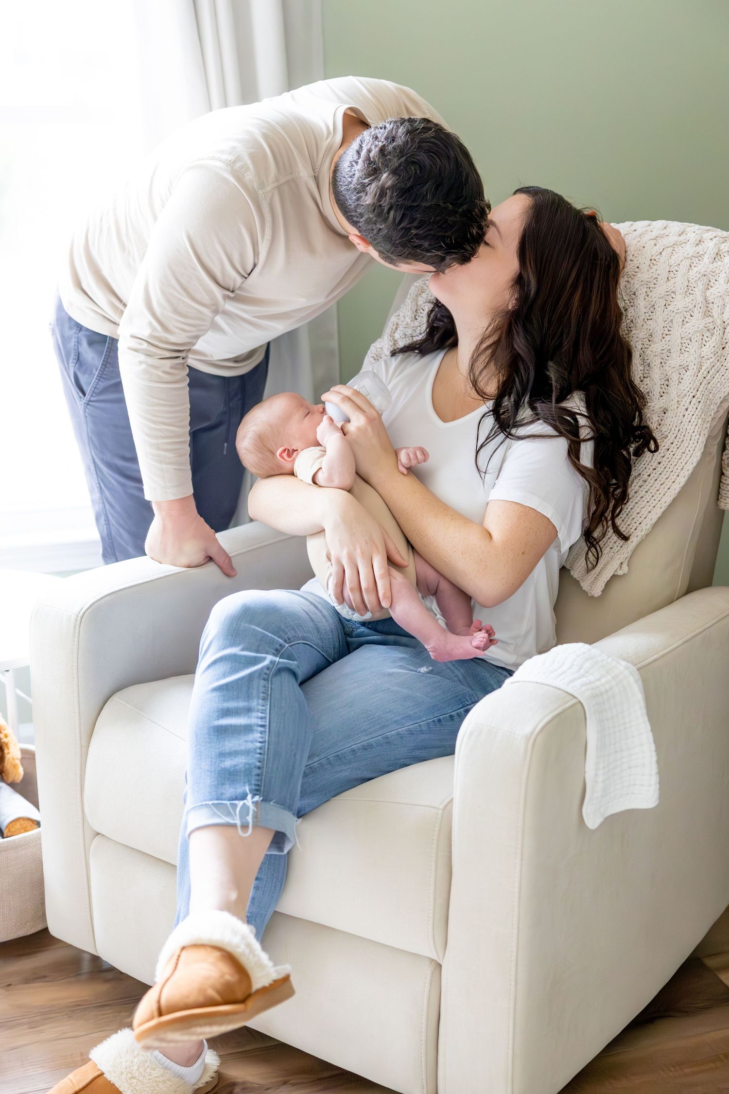 Tender moment in white nursery chair with infant.