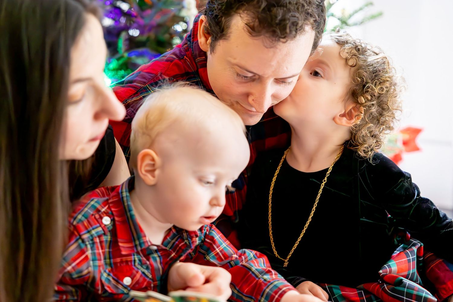Intimate family moment during Christmas celebration with festive plaid outfits.