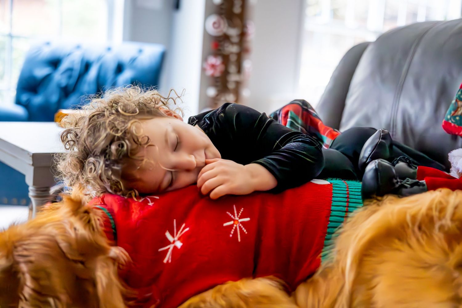 A sleeping child rests on the family golden retriever.
