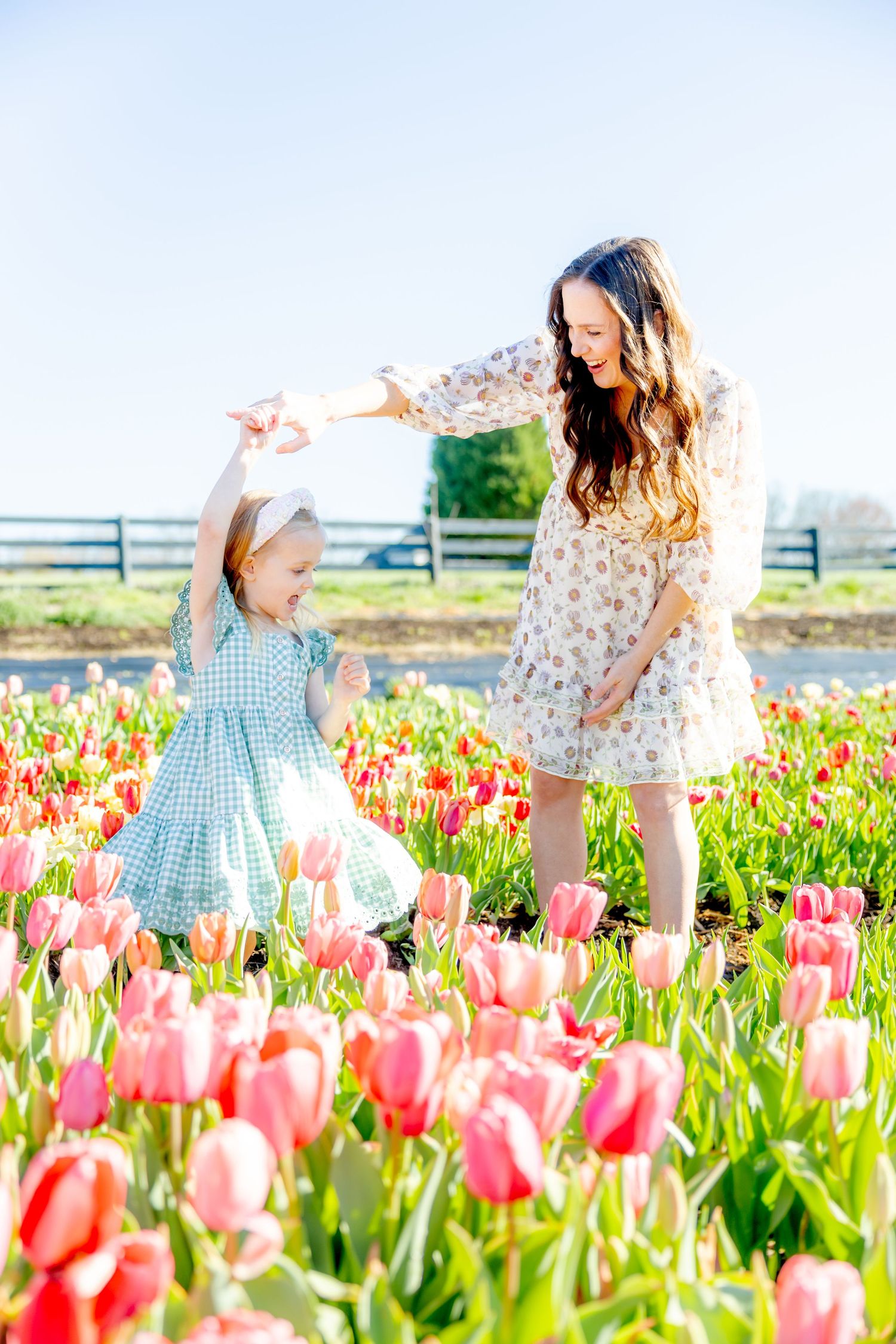 Springtime photoshoot in vibrant pink tulip field on sunny day.