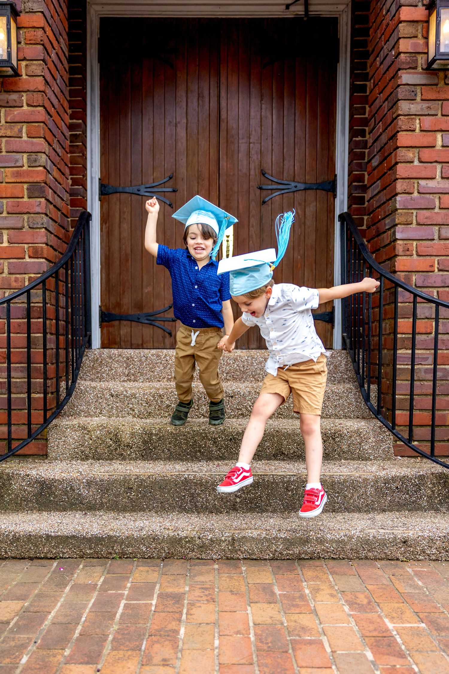 Dynamic jumping sequence of preschool graduates on concrete steps in graduation attire.