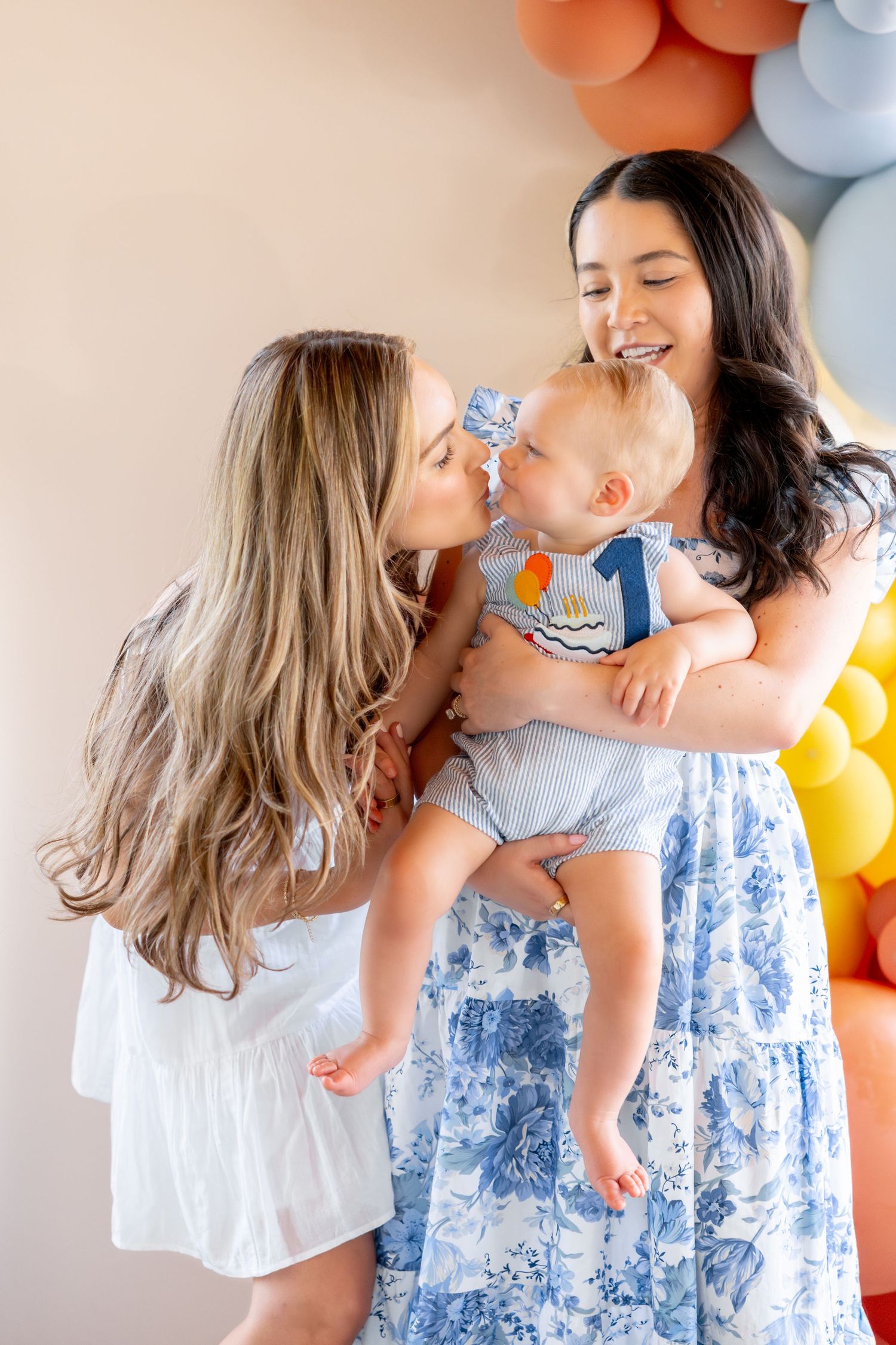 Sweet family moment with balloon decorations in pastel colors at first birthday celebration.
