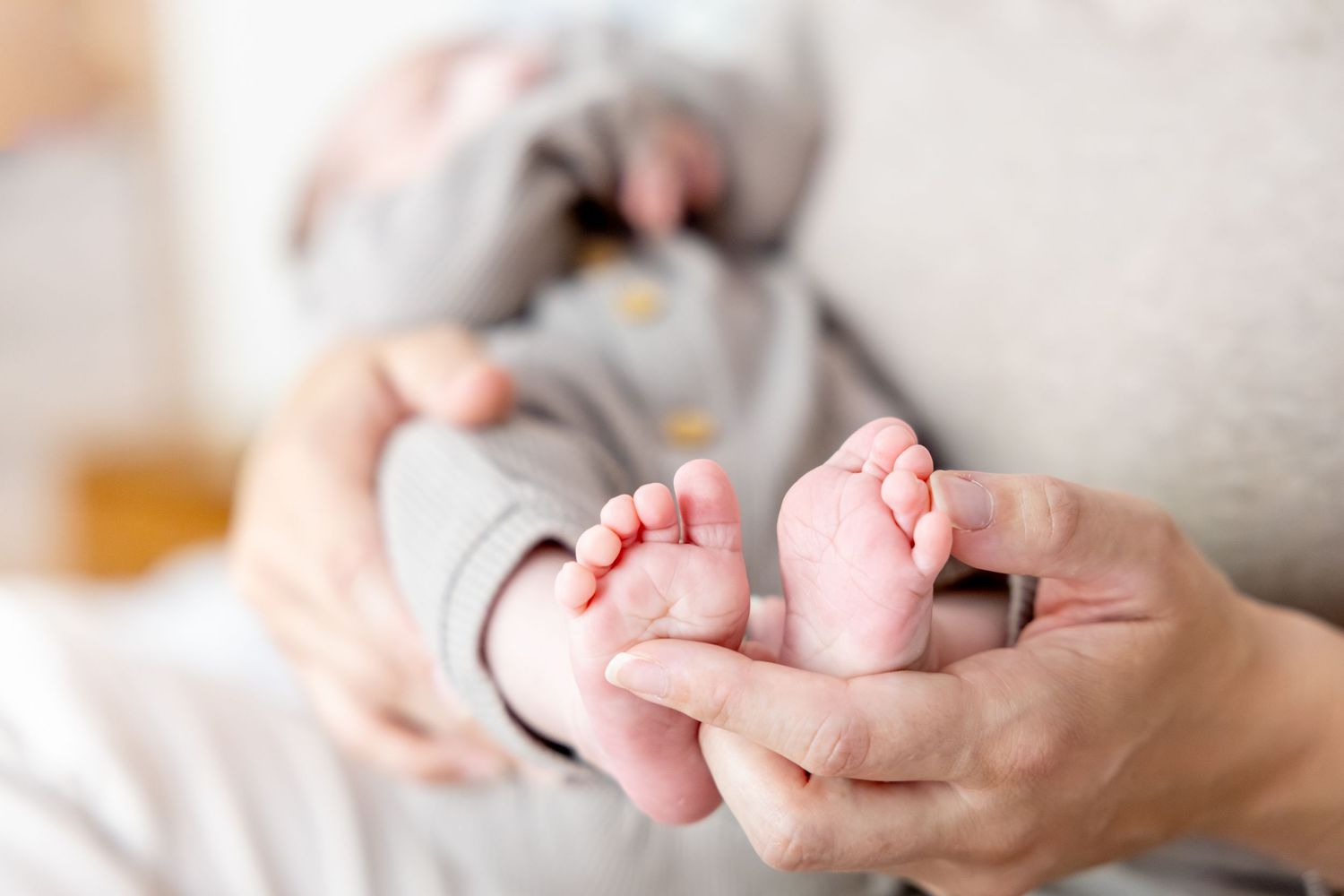 Close up view of tiny baby feet being gently held in adult hands.