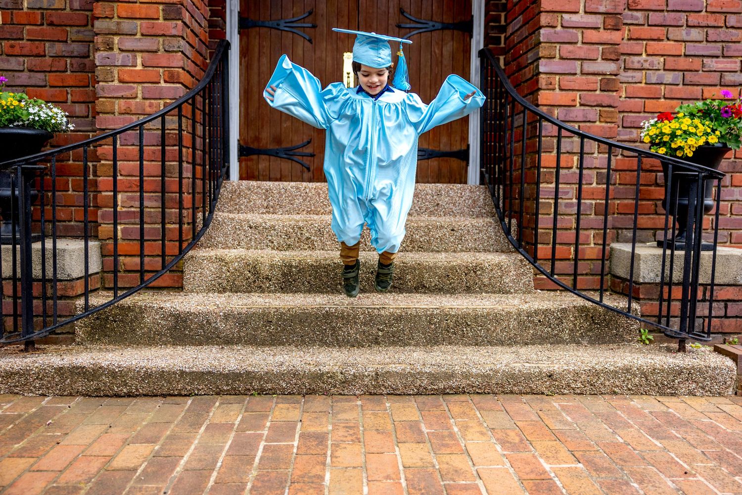 A sequence of energetic poses from preschool graduate on brick steps wearing a blue graduation gown and cap.