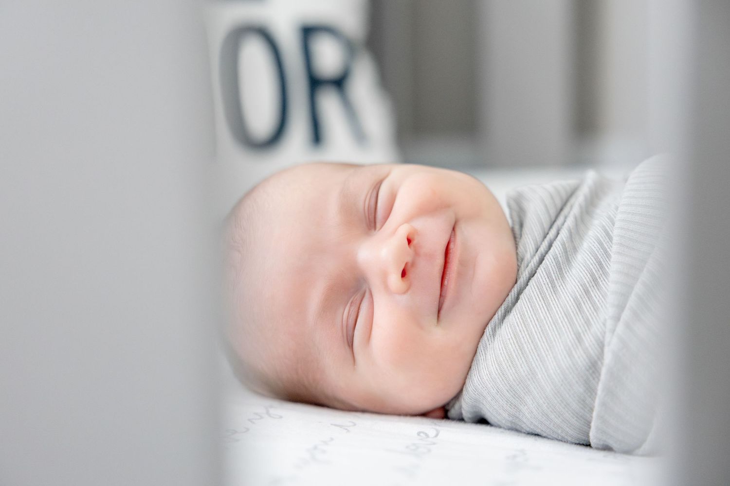 Serene baby resting on white surface in natural light.