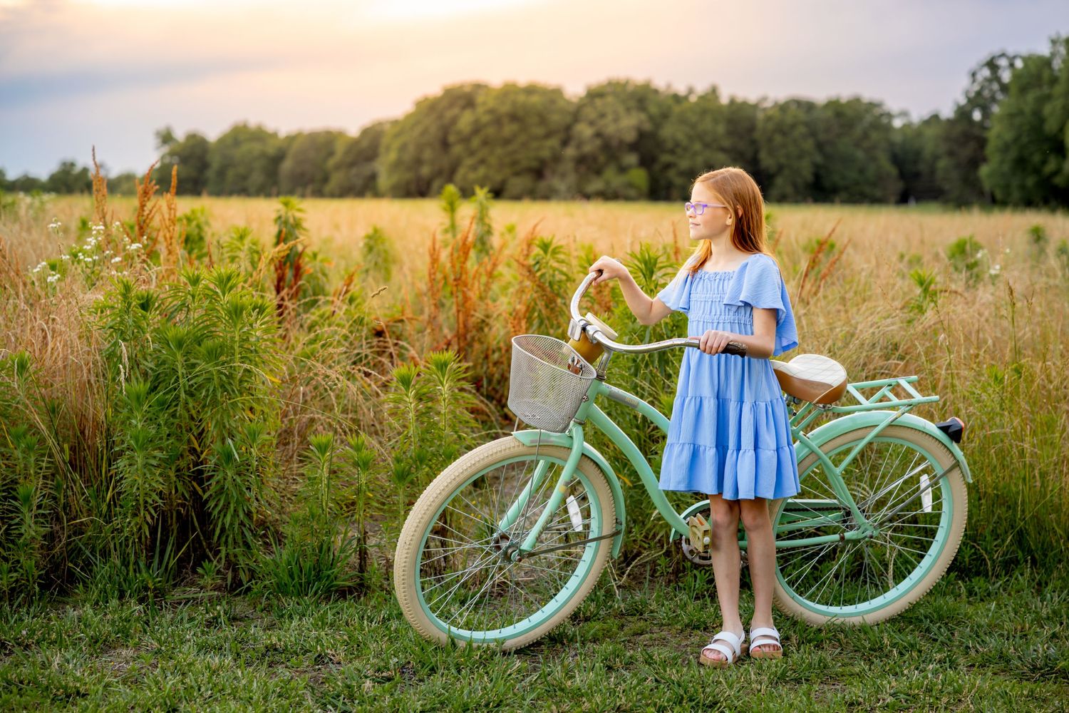 A rustic mint green vintage bicycle parked in a golden summer field during sunset at Blue Hill Garden in Monroe, NC.