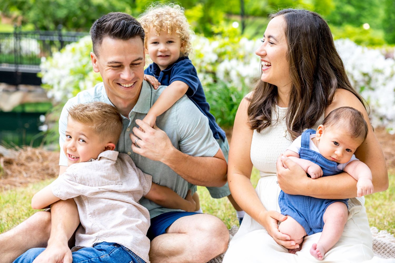 Cheerful family enjoying a fun outdoor photoshoot in a lush green setting.