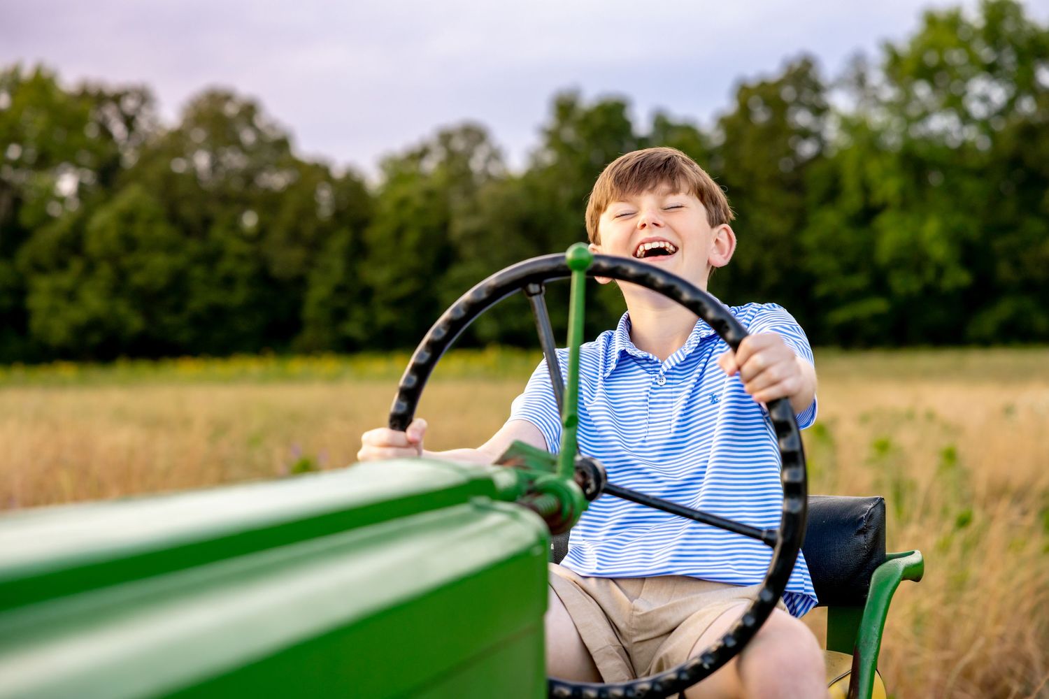 Outdoor lifestyle photography session with green tractor and natural summer scenery at Blue Hill Garden in Monroe, NC.