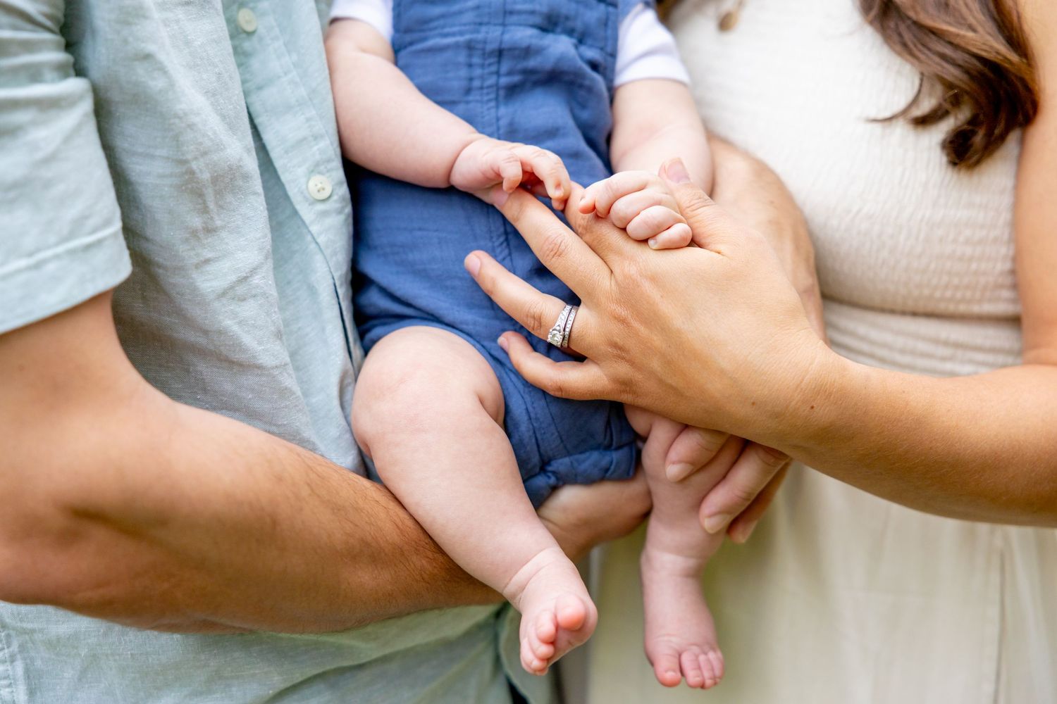 Close-up shot of hands tenderly holding in an outdoor setting.