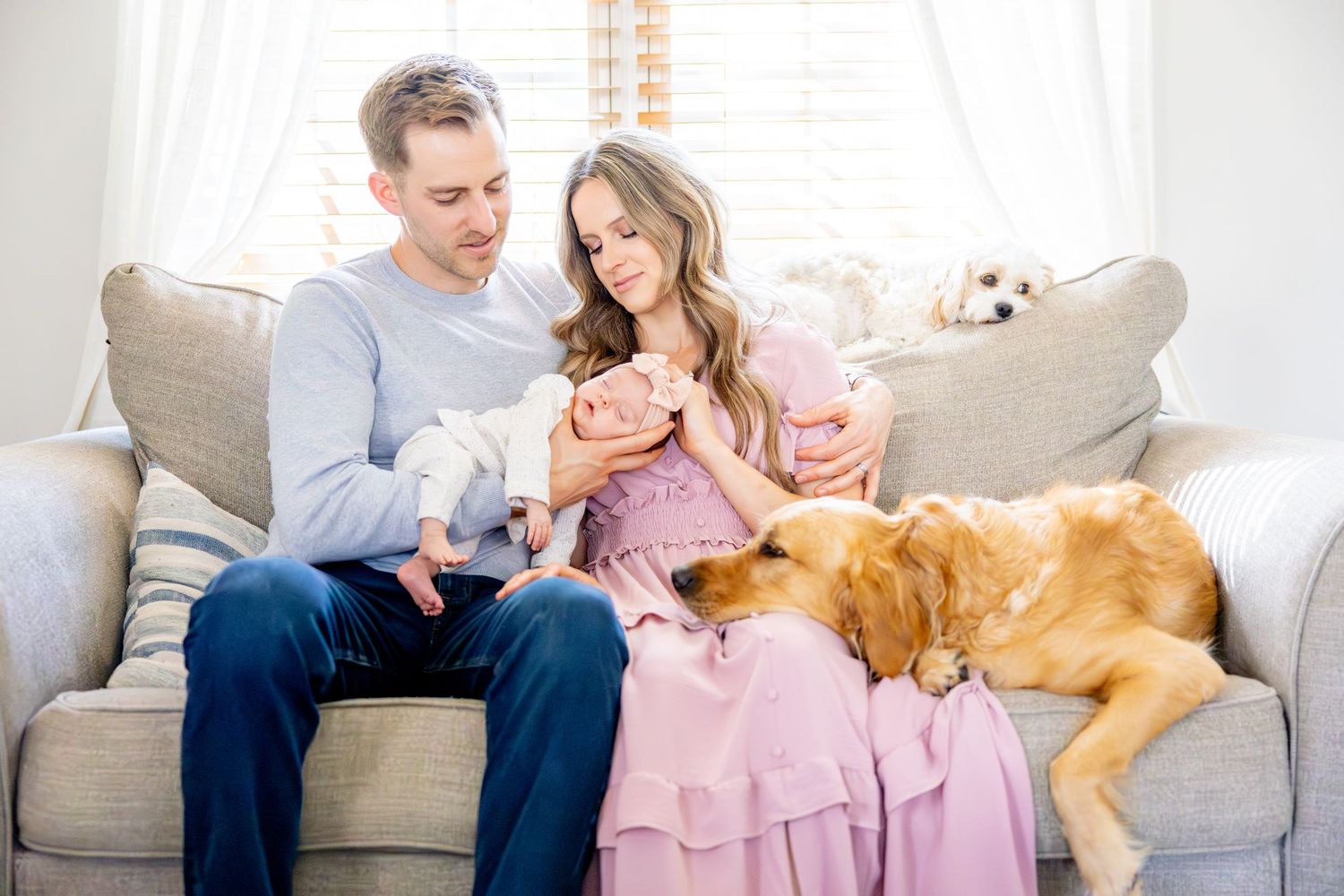 Family relaxing on sofa with pets including golden retriever and small animals.