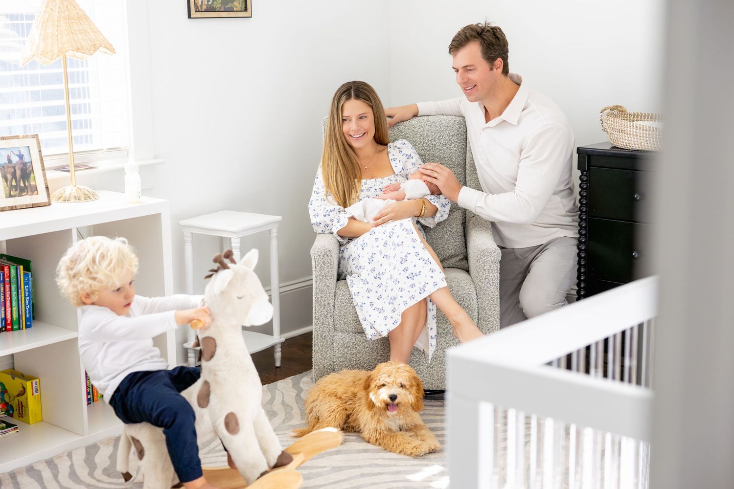 Family spends quality time together in nursery with dog and toddler playing nearby.