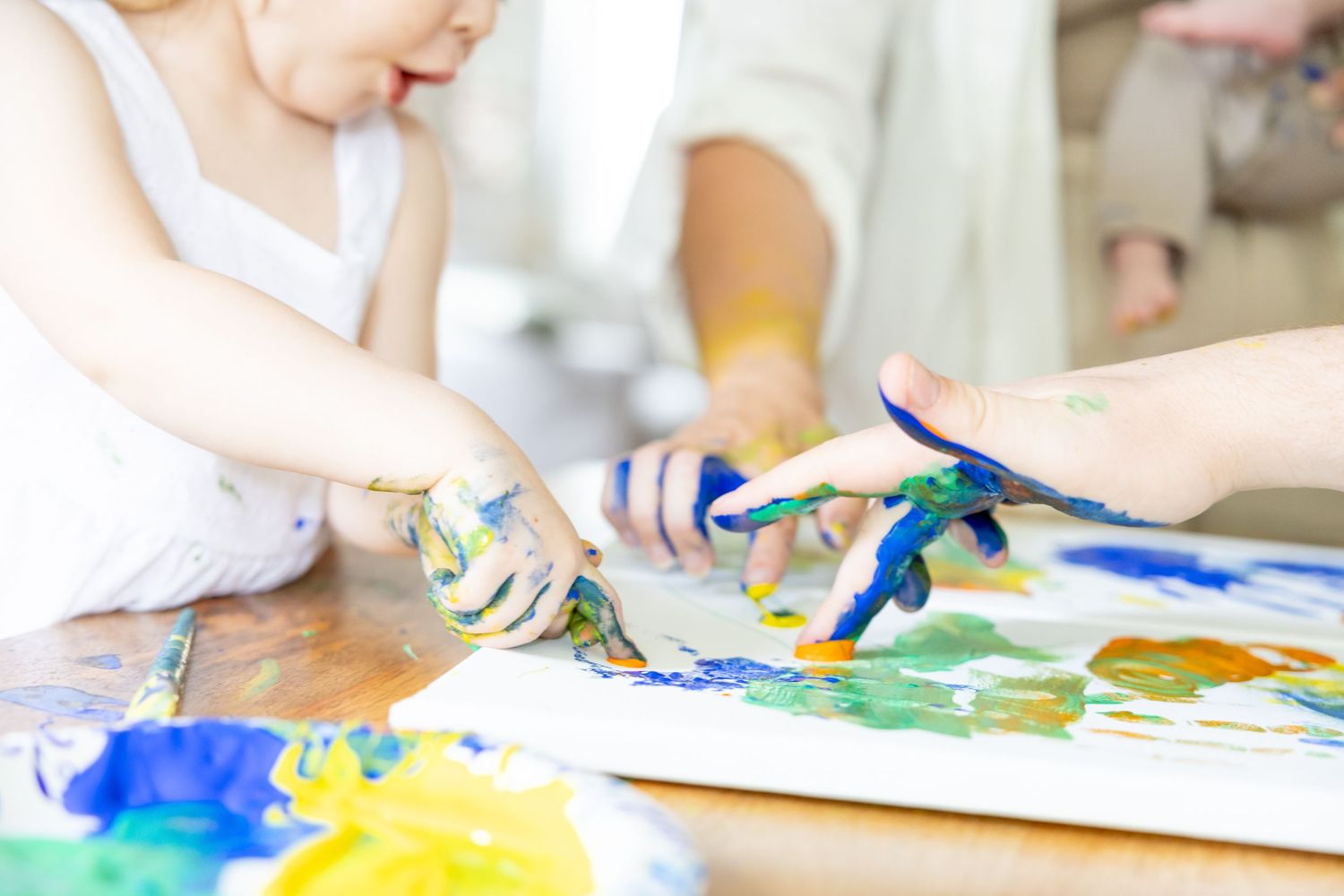 Finger painting activity with blue and yellow paints spread on white paper.