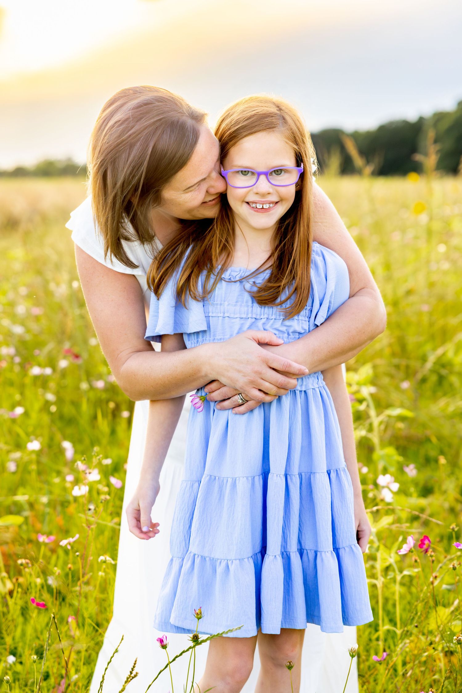 Tender embrace in a sunlit wildflower meadow wearing white and blue dresses on a summer evening at Blue Hill Garden in Monroe, NC.