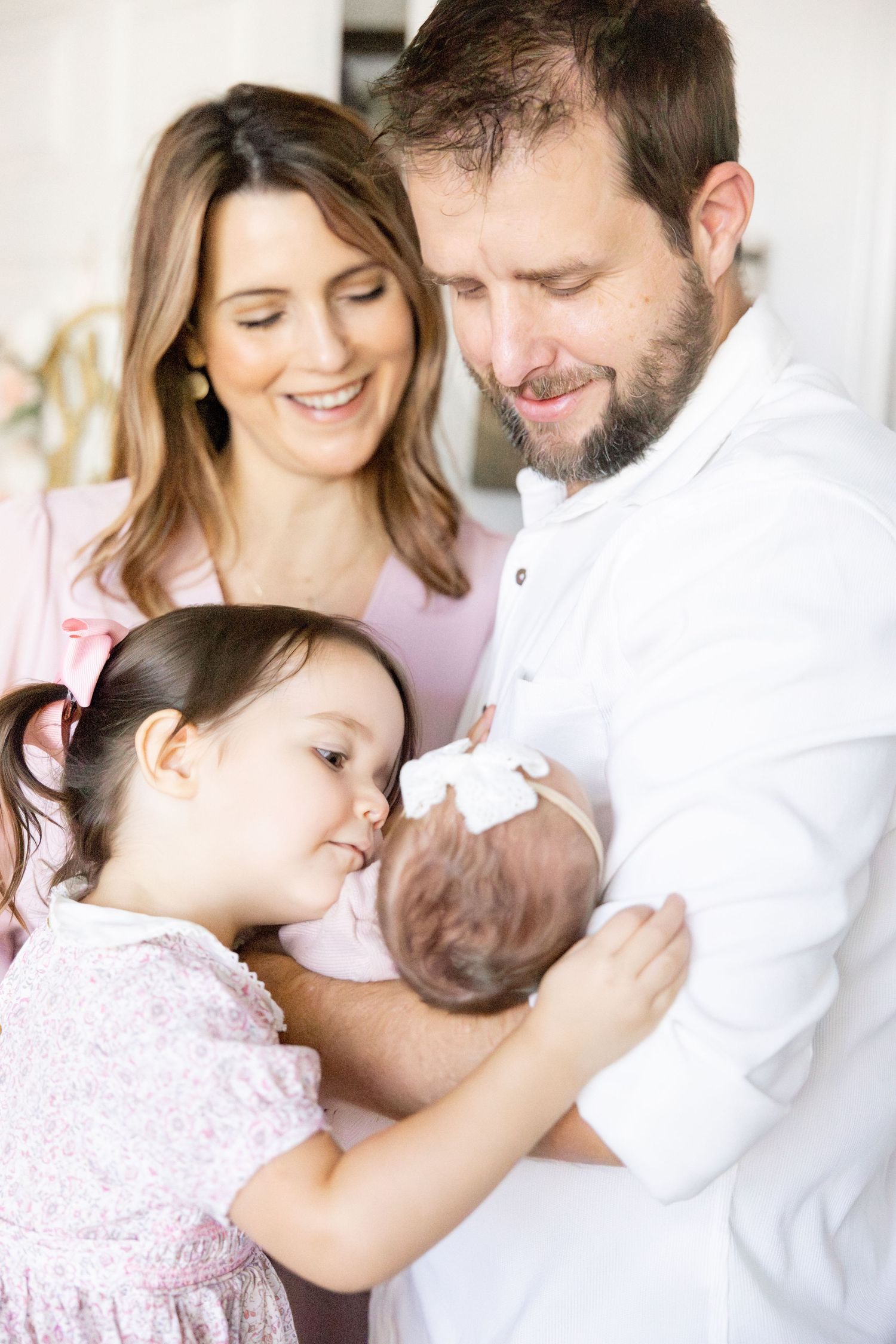 Loving family moment captured in soft pastel tones with newborn baby.