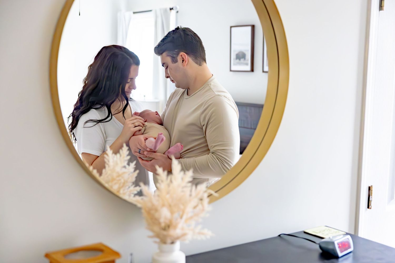 Family reflection in round gold mirror with baby and cat.