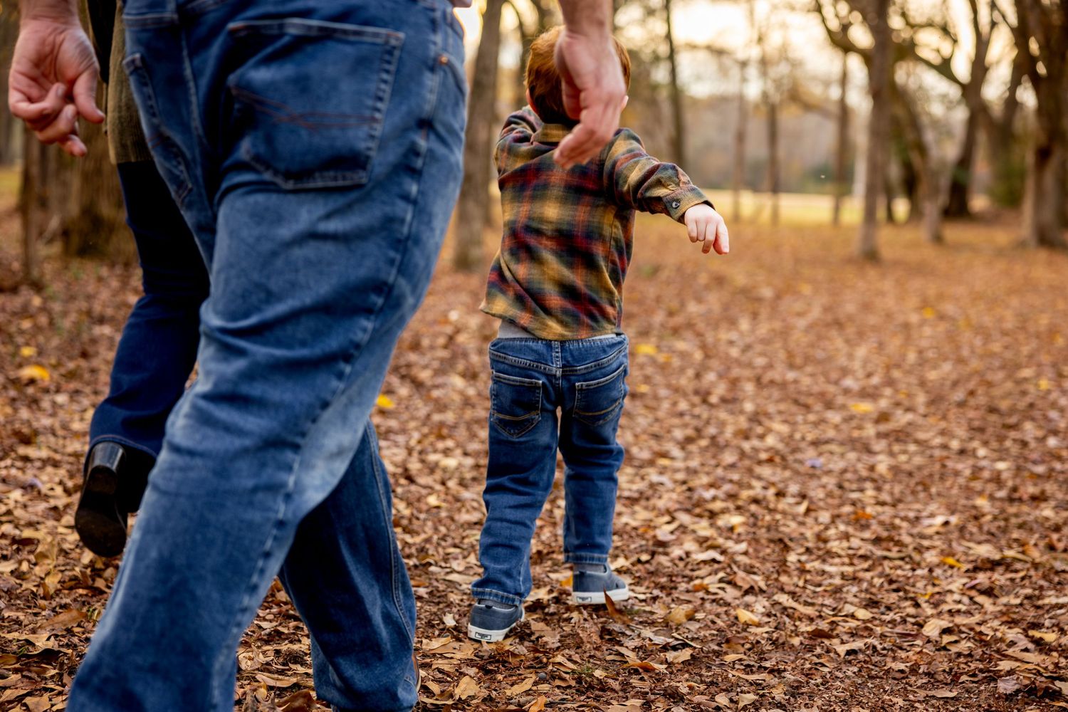 Candid shots of family members' feet and legs walking through fallen autumn leaves.
